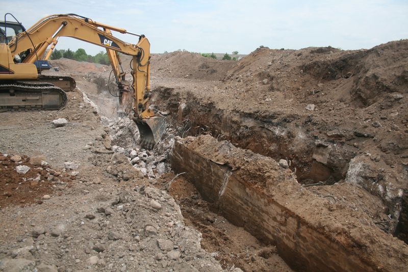 Excavator pulling concrete out of a trench