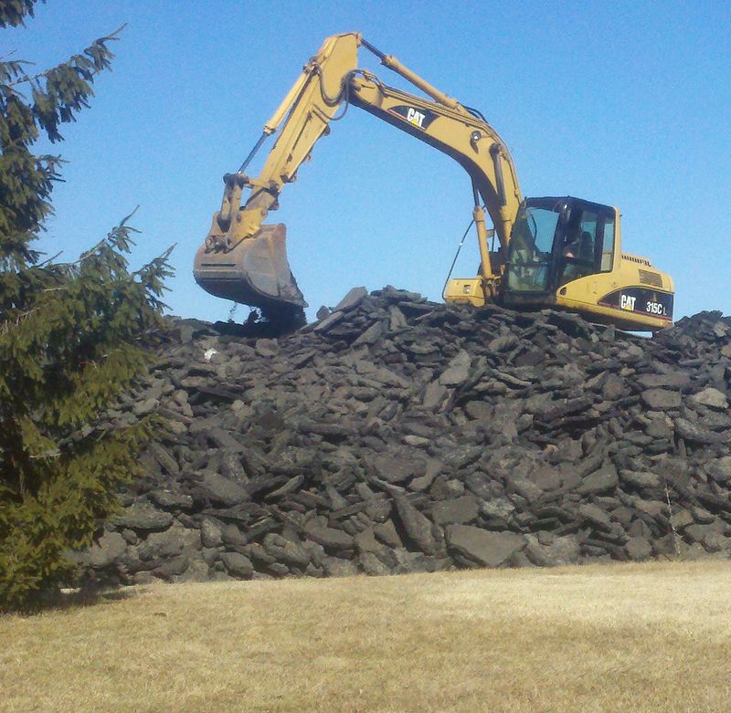 Excavator on a pile of demolition debris
