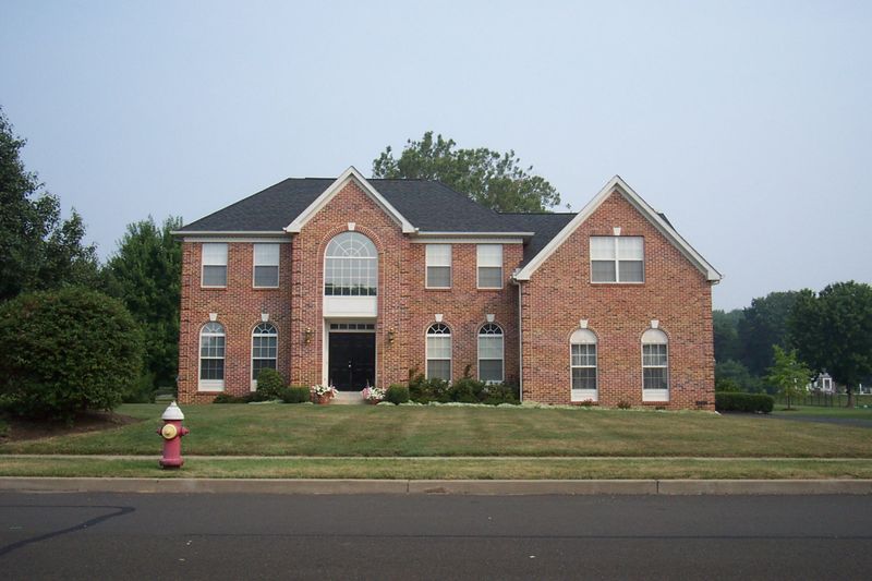 Two-story all-brick colonial with arched windows, seen from the street