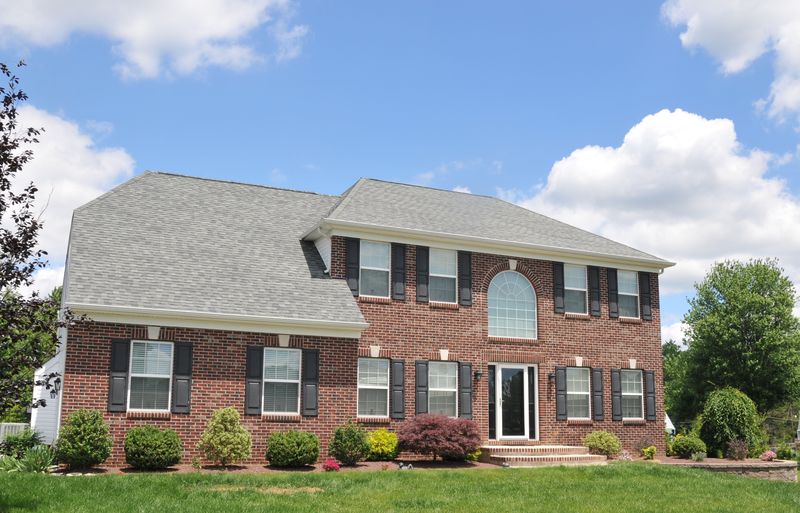 Brick-front colonial with an arched window and gray roof