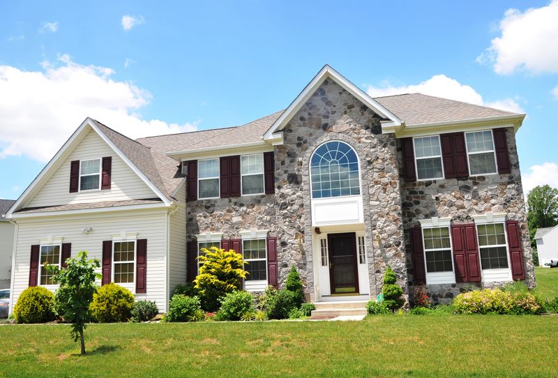 Colonial with a fieldstone front, an arched window and burgundy shutters