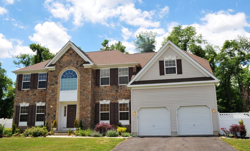 Colonial with a stone front, arched window and two-car front garage