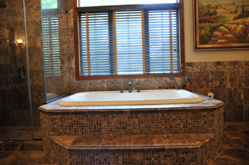 Soaking tub with a mosaic tile surround below a window